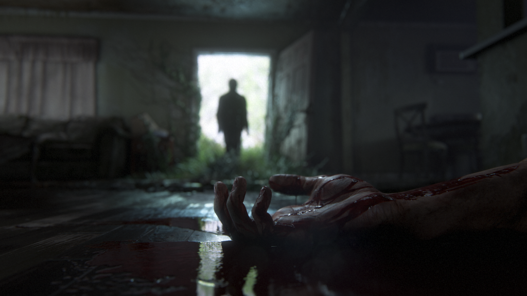 A photorealistic scene from The Last Of Us: Part 2. A blood-covered arm rests on the floor of a grey, abandoned house. In the background, a person's silhouette stands in front of a lit doorway.
