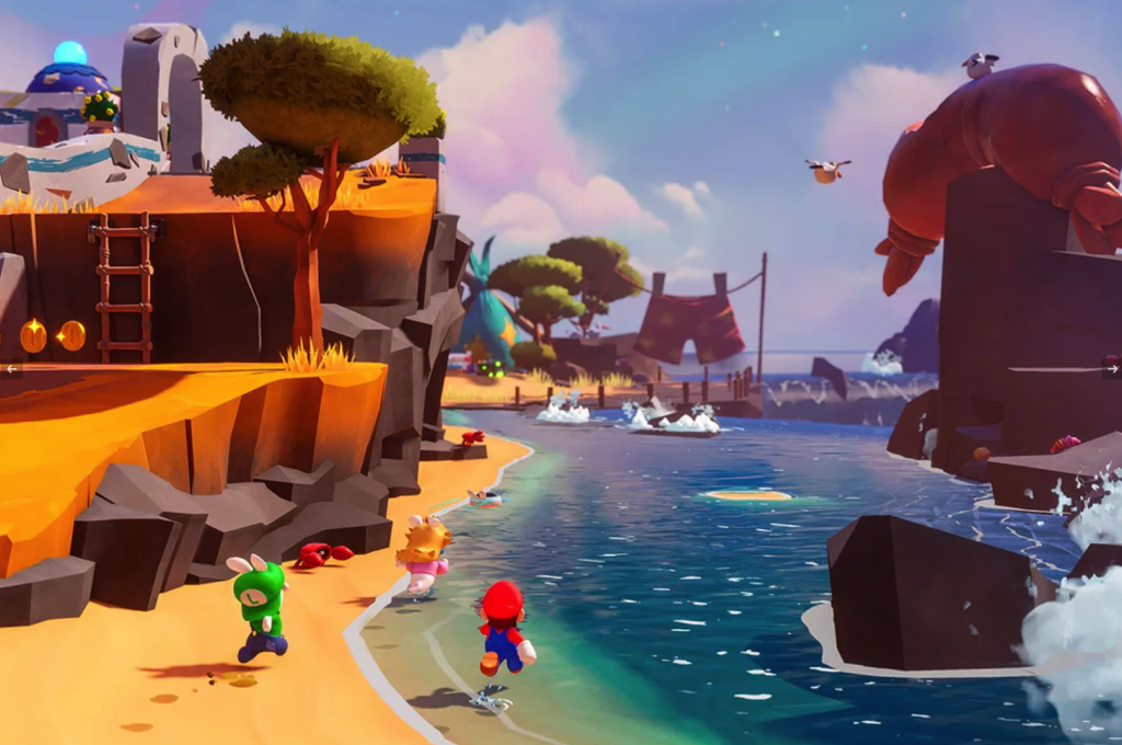 A cartoony 3D image from Mario + Rabbids: Sparks of Hope. Mario, Rabbid Luigi, and Rabbid Peach stand with their backs to the camera on a beach. A cliff rises up to the left, on which there is a tree, a ladder to a higher level, two coins, and an enemy in front of a stone arch. To the right is water, and in the distance, a giant pair of underpants hangs on a clothesline. To the far right of the image, a giant walrus lies on a rock that's a couple stories high. 