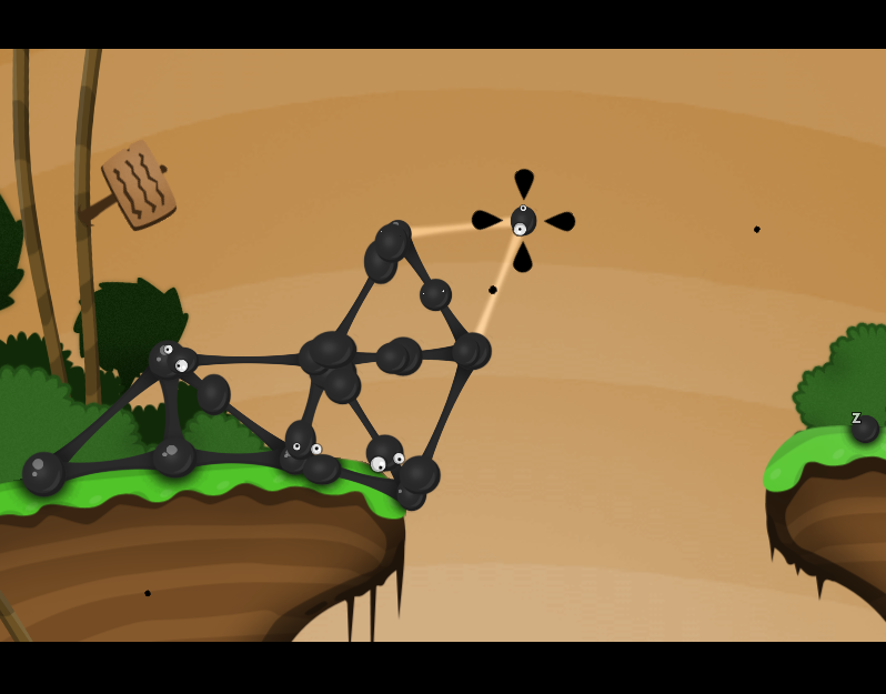 A stylized, cartoon screen capture from World of Goo. A black lattice sits at the edge of a cliff, against an orange sky. Black goo balls with goggly eyes crawl along the lattice, and one goo ball is floating above the lattice.  Another goo ball rests on a cliff at the other side of the screen.